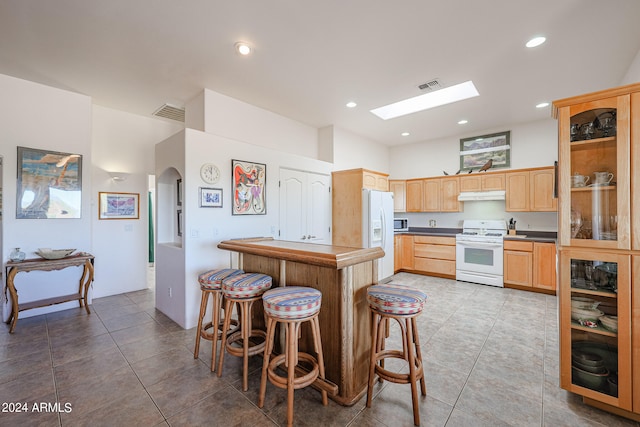 kitchen featuring a skylight, light brown cabinets, light tile patterned floors, and white appliances