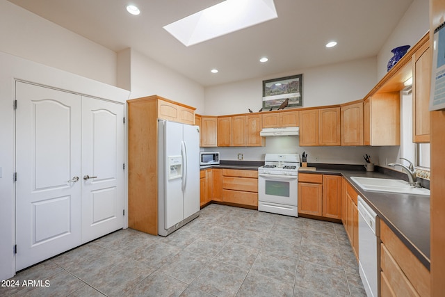 kitchen with white appliances, a skylight, and sink