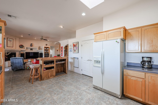 kitchen featuring ceiling fan, white refrigerator with ice dispenser, and light brown cabinetry