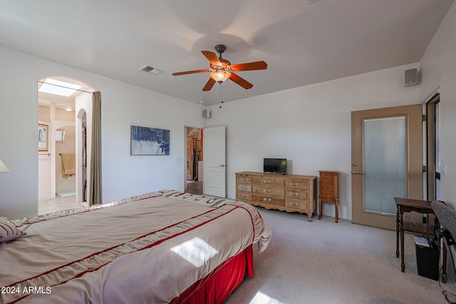 bedroom with ceiling fan, ensuite bathroom, and light colored carpet