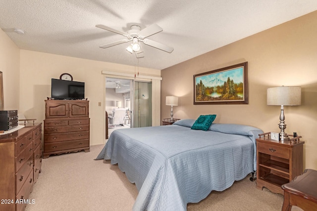 bedroom featuring ceiling fan, light colored carpet, and a textured ceiling