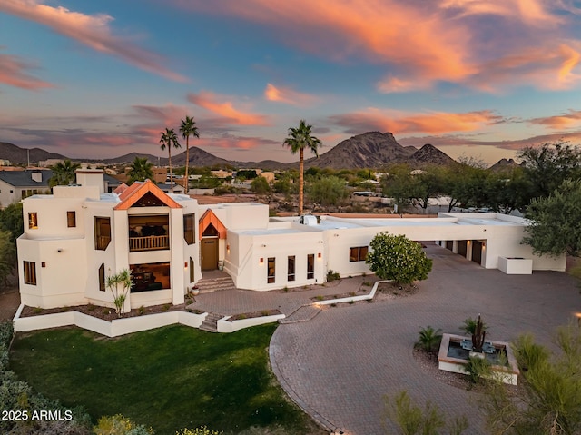 view of front of house featuring a balcony, a mountain view, and a lawn