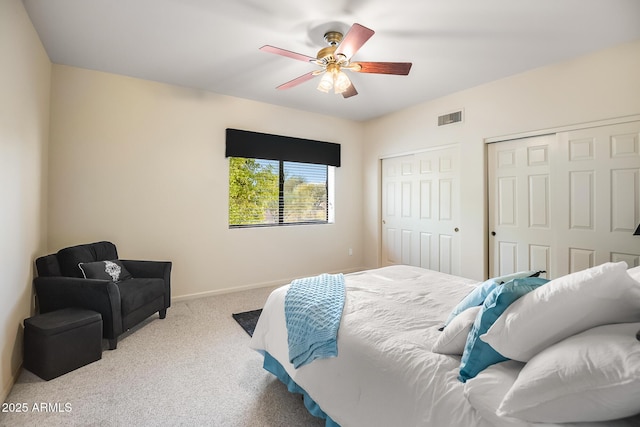 bedroom featuring light carpet, two closets, and ceiling fan