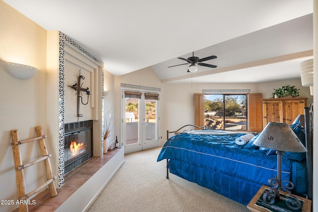 bedroom with multiple windows, a tiled fireplace, lofted ceiling, and access to outside