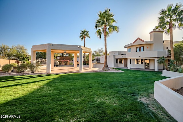 back of house with a balcony, a patio area, and a lawn