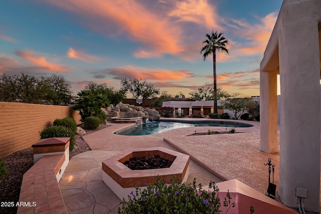 pool at dusk featuring an outdoor fire pit and a patio area