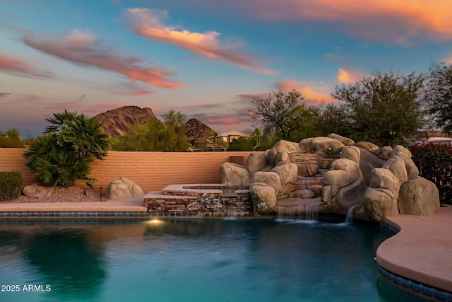 pool at dusk featuring pool water feature