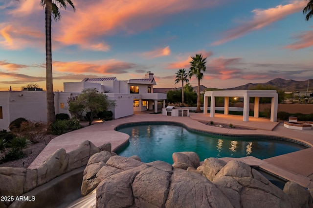 pool at dusk with a mountain view and a patio area