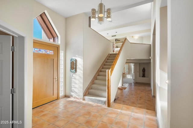 tiled entrance foyer featuring a towering ceiling and a notable chandelier