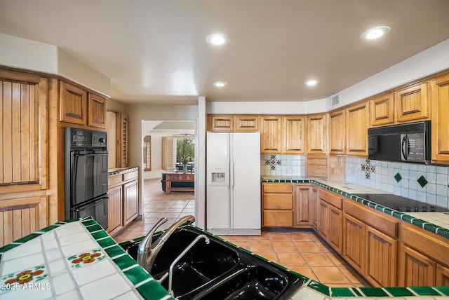 kitchen featuring backsplash, tile counters, black appliances, and light tile patterned flooring