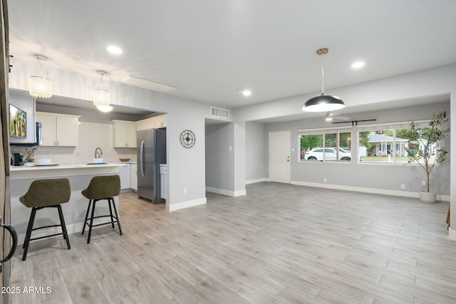 living room featuring recessed lighting, baseboards, and light wood-type flooring