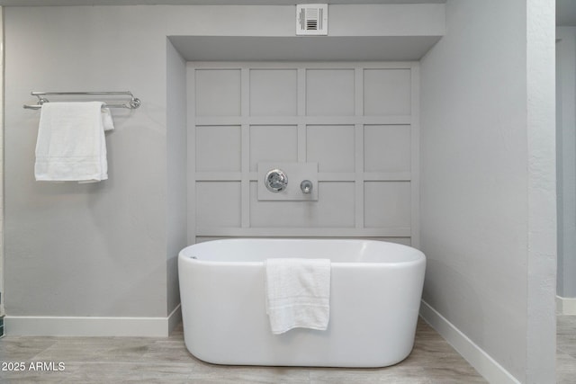 bathroom with baseboards, a soaking tub, and wood finished floors