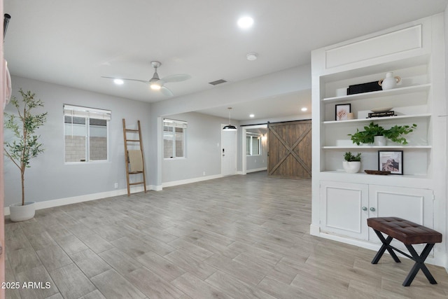 unfurnished living room featuring a barn door, baseboards, a ceiling fan, light wood finished floors, and recessed lighting
