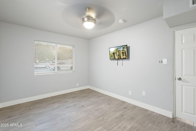 spare room with ceiling fan, light wood-style floors, baseboards, and a smoke detector