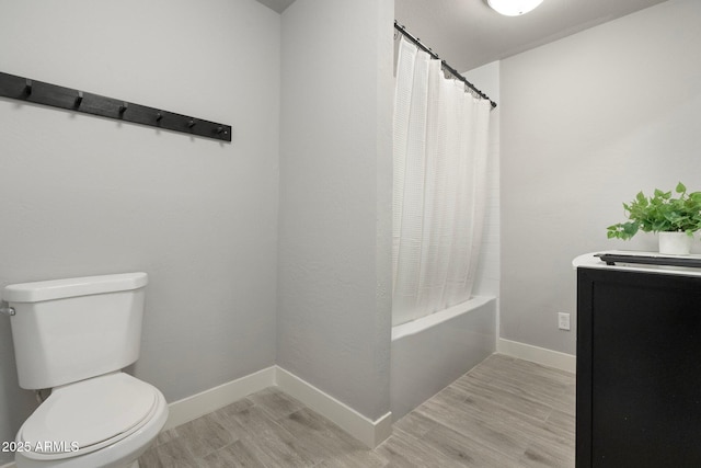 bathroom featuring wood finished floors, toilet, baseboards, shower / bath combo, and vanity