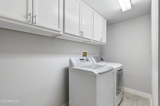 clothes washing area with cabinet space, washing machine and dryer, light wood finished floors, and baseboards