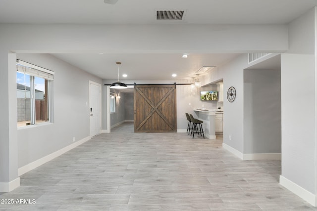 basement with a barn door, baseboards, recessed lighting, and light wood-style flooring