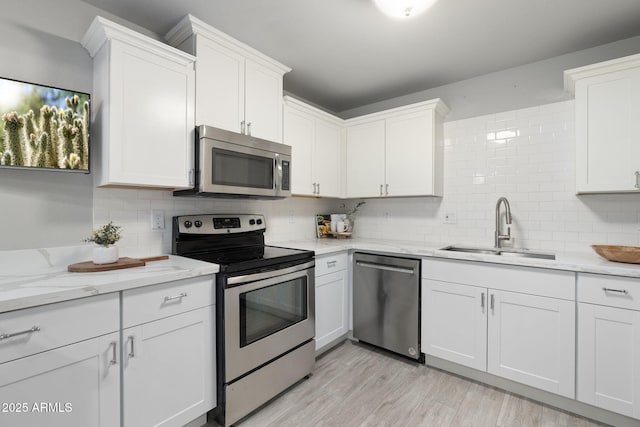kitchen featuring appliances with stainless steel finishes, a sink, backsplash, and white cabinets