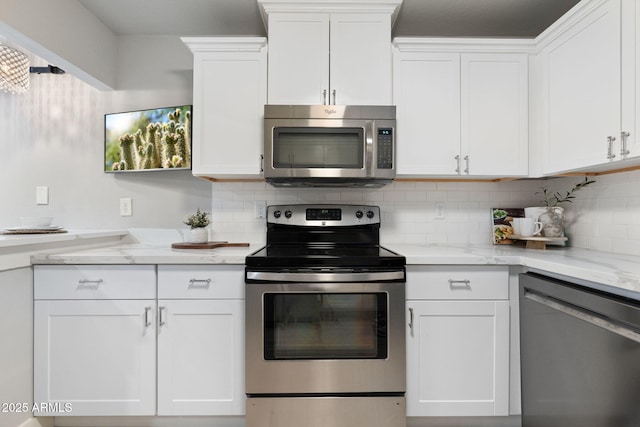 kitchen featuring appliances with stainless steel finishes, white cabinets, backsplash, and light stone countertops