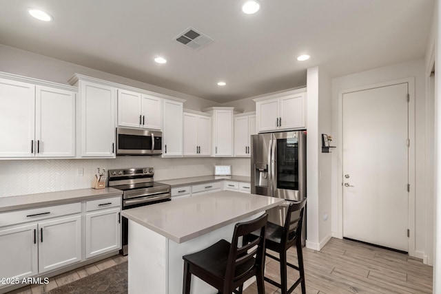 5460 S Dillon Cir, Mesa, AZ 85212 - kitchen featuring stainless steel appliances, light wood-style floors, white cabinetry, a kitchen breakfast bar, and light countertops