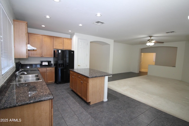 kitchen with arched walkways, recessed lighting, visible vents, black fridge with ice dispenser, and a sink