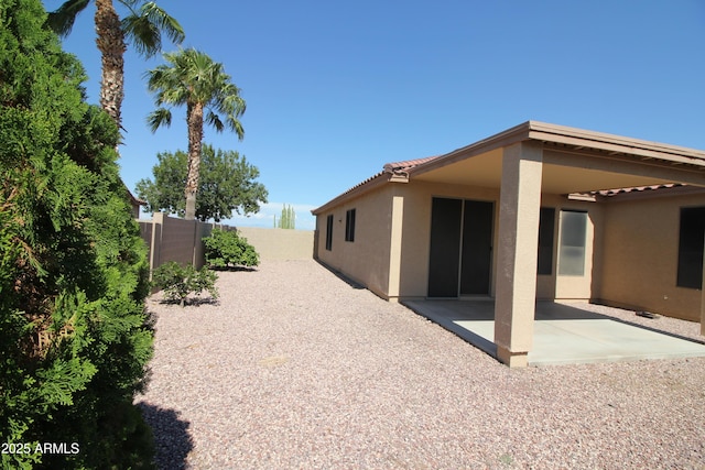 exterior space featuring stucco siding, a fenced backyard, a tiled roof, and a patio