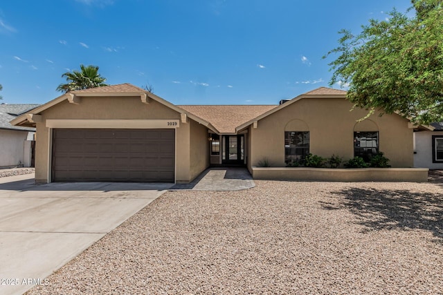 ranch-style house with driveway, stucco siding, roof with shingles, and an attached garage
