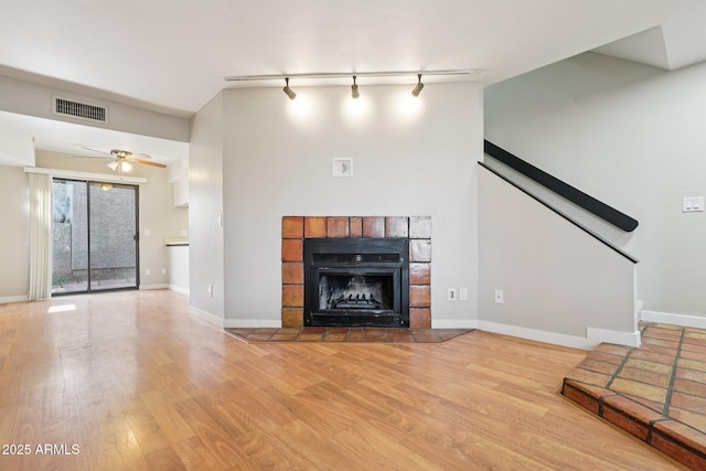 2815 N 52nd St Unit 3, Phoenix, AZ 85008 - unfurnished living room featuring wood finished floors, rail lighting, ceiling fan, and a tile fireplace