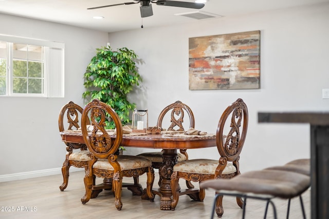 dining room featuring visible vents, light wood-style flooring, a ceiling fan, and baseboards