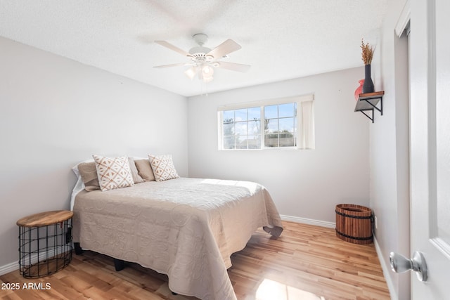 bedroom featuring wood finished floors, baseboards, and a textured ceiling