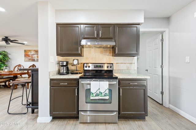 kitchen featuring stainless steel electric stove, dark brown cabinetry, under cabinet range hood, light wood-type flooring, and backsplash