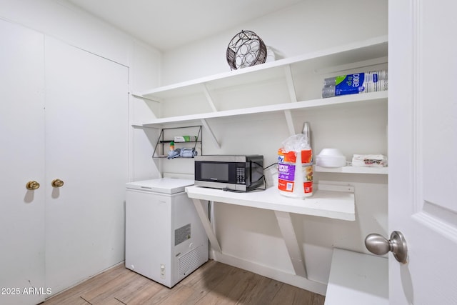 clothes washing area with light wood-style floors