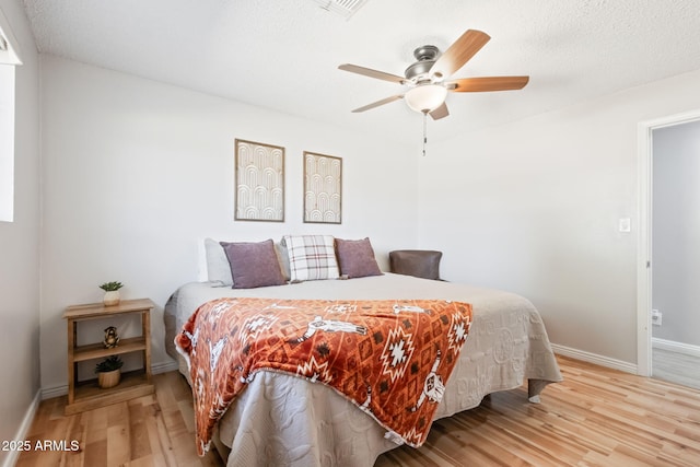 bedroom featuring visible vents, a ceiling fan, baseboards, and light wood finished floors