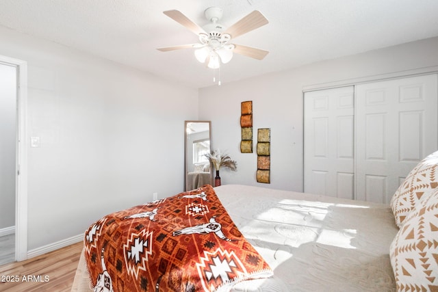 bedroom featuring a closet, baseboards, light wood-type flooring, and ceiling fan