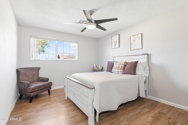 bedroom featuring light wood finished floors, visible vents, and a textured ceiling