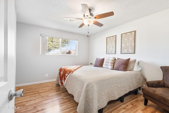 bedroom featuring baseboards, visible vents, a textured ceiling, and light wood-style floors