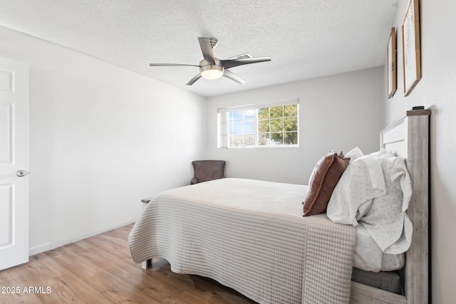 bedroom with a ceiling fan, wood finished floors, and a textured ceiling