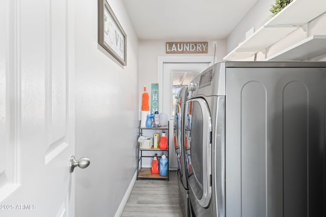 laundry area featuring baseboards, separate washer and dryer, wood finished floors, and laundry area