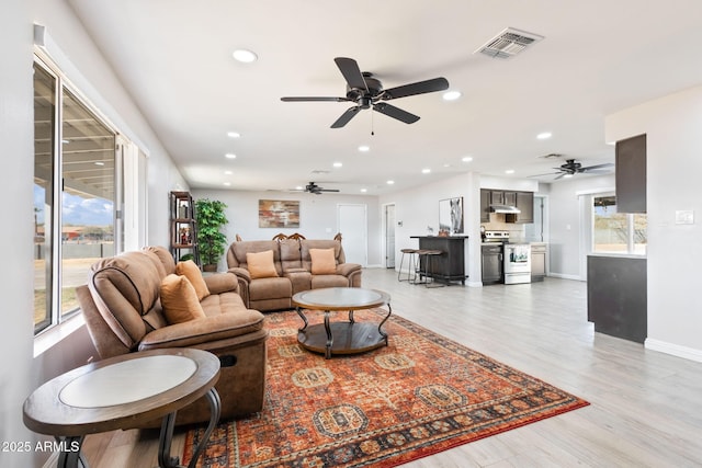 living room with recessed lighting, visible vents, light wood finished floors, and baseboards