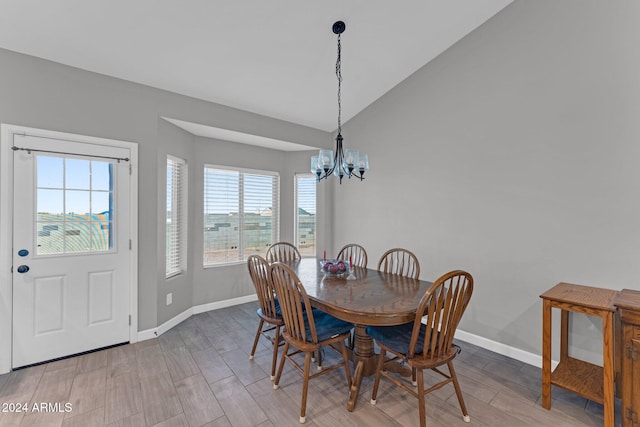 dining room with light wood-type flooring, a healthy amount of sunlight, vaulted ceiling, and a chandelier