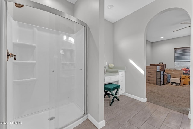 bathroom featuring a shower with door, vanity, and ceiling fan