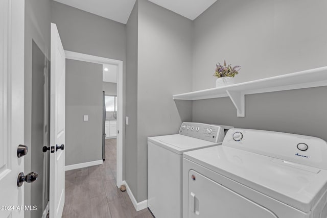 laundry room with light hardwood / wood-style floors and washing machine and clothes dryer