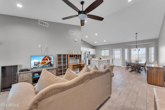 living room with high vaulted ceiling, light hardwood / wood-style flooring, and ceiling fan with notable chandelier