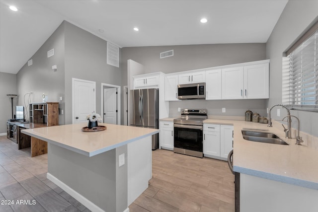 kitchen featuring white cabinets, appliances with stainless steel finishes, light wood-type flooring, sink, and a center island