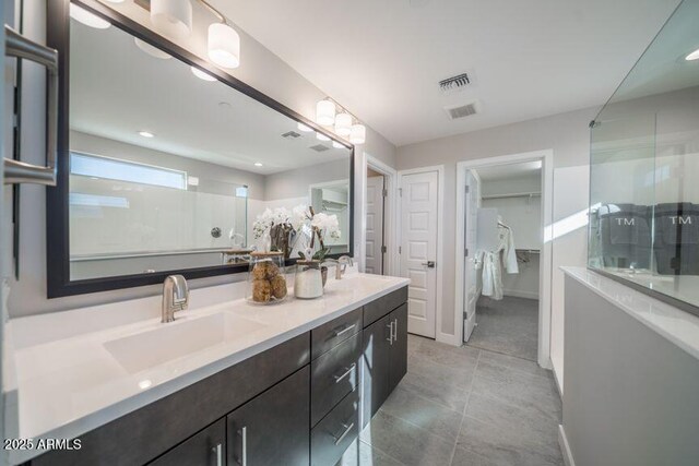 12233 W Caraveo Pl, Peoria, AZ 85383 - bathroom featuring a shower with door, double vanity, a spacious closet, baseboards, and tile patterned flooring