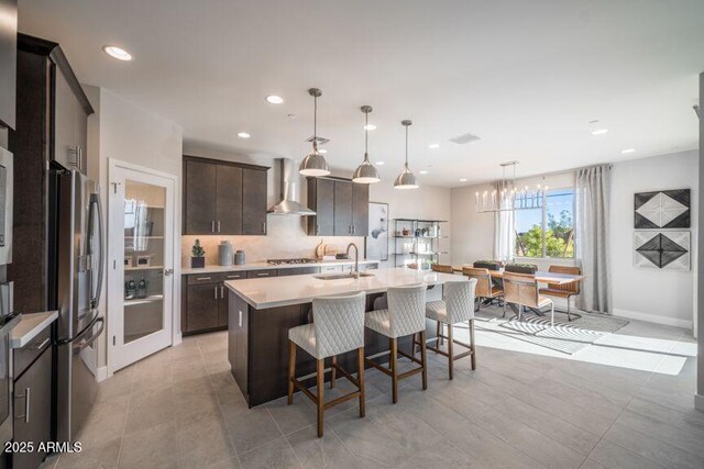 12233 W Caraveo Pl, Peoria, AZ 85383 - kitchen with a sink, wall chimney range hood, stainless steel appliances, light countertops, and dark brown cabinets
