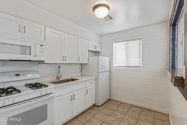 3128 W Pima St Unit 2, Phoenix, AZ 85009 - kitchen with white appliances, white cabinetry, light tile patterned floors, light countertops, and brick wall