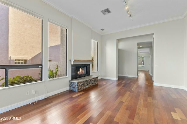 unfurnished living room featuring hardwood / wood-style flooring, crown molding, plenty of natural light, and a fireplace