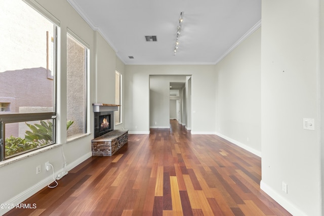 unfurnished living room featuring crown molding, a stone fireplace, dark hardwood / wood-style flooring, and rail lighting