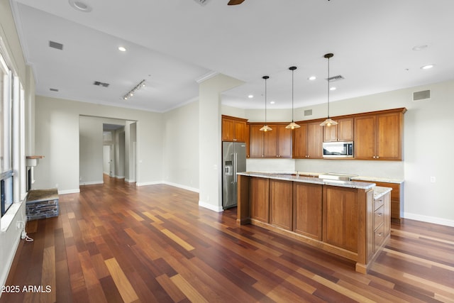 kitchen with a kitchen island, appliances with stainless steel finishes, hanging light fixtures, light stone counters, and dark wood-type flooring